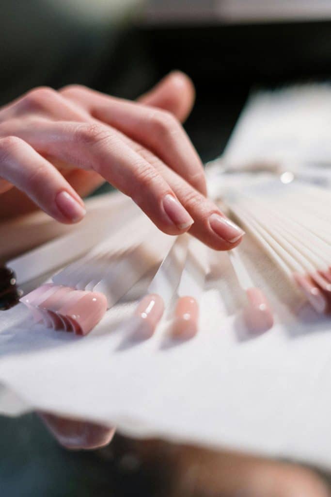 A close-up of a hand selecting nail polish color samples in a beauty salon.
